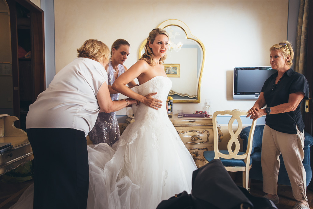 La damigelle sistemano il vestito della sposa