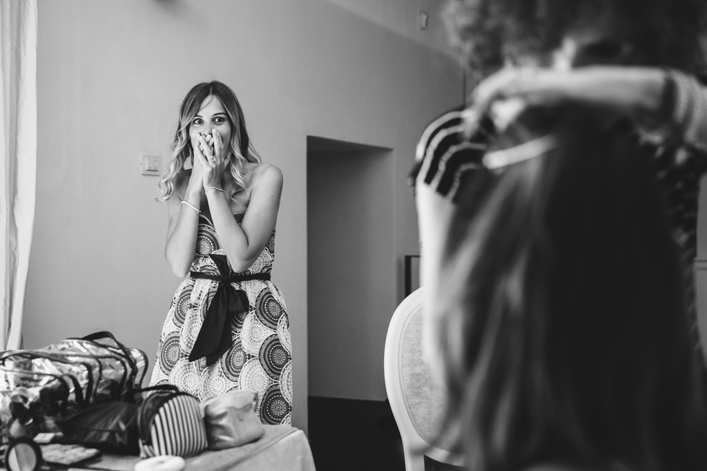 Fotografo Matrimonio Villa Caroli Zanchi Una damigella in un'espressione basita osserva la splendida acconciatura della sposa in uno scatto del fotografo Alessandro Della Savia