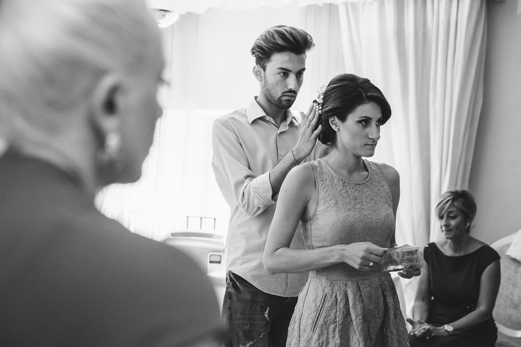 Fotografo Matrimonio Villa Caroli Zanchi Il parrucchiere perfeziona gli ultimi dettagli dei capelli della sposa