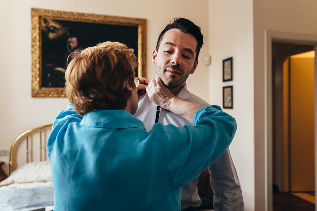 Fotografo Matrimonio Monza La madre adorna Simone durante la preparazione
