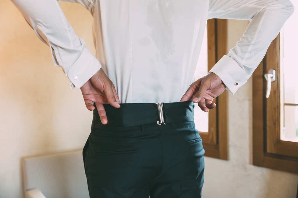 Lo sposo aggiusta i pantaloni in preparazione della cerimonia