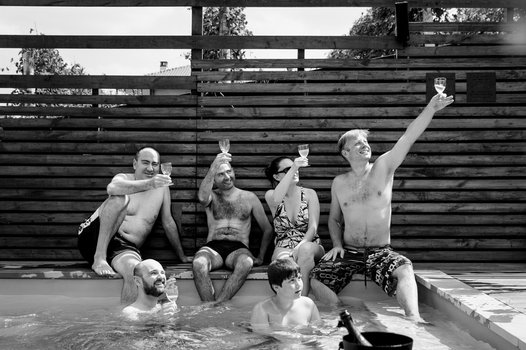 Fotografo Matrimonio Langhe Lo sposo brinda in piscina in compagnia dei testimoni in uno scatto di Alessandro Della Savia