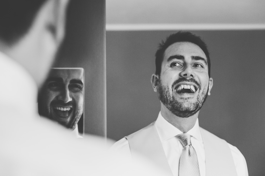 Fotografo Matrimonio Pavia Un invitato sorride davanti allo specchio in uno scatto di Della Savia, fotografo di Milano