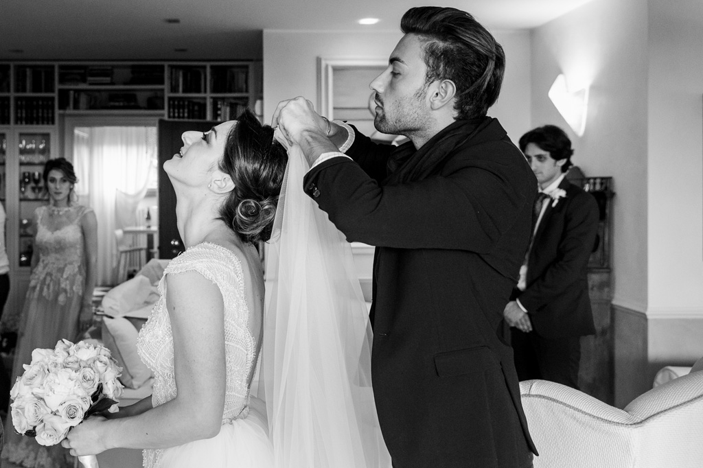 Fotografo Matrimonio Monza Un testimone sistema il velo della sposa