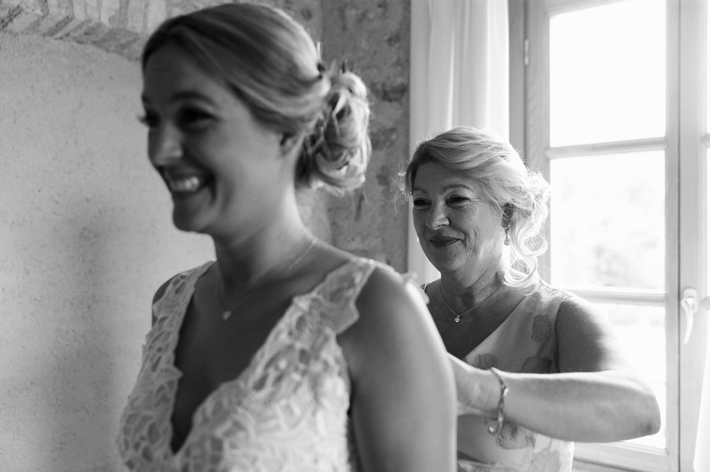 La madre della sposa sistema con cura il vestito della figlia