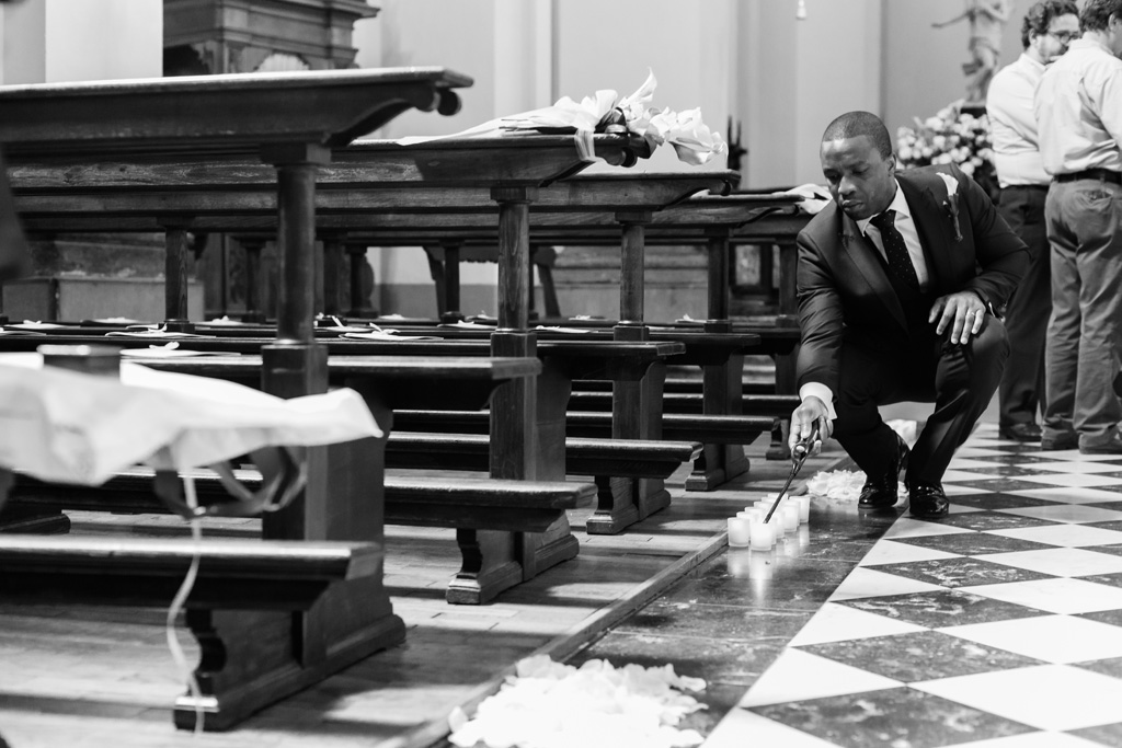 Fotografo Matrimonio Villa Erba Un invitato accende le candele all'interno della chiesa di Sant'Abbondio presso Como