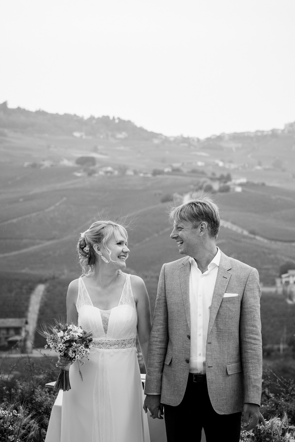 Fotografo Matrimonio Langhe La sposa è in compagnia dello sposo sullo sfondo affascinante paesaggio campestre