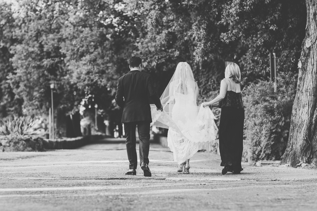La madre sostiene il vestito della sposa durante una passeggiata