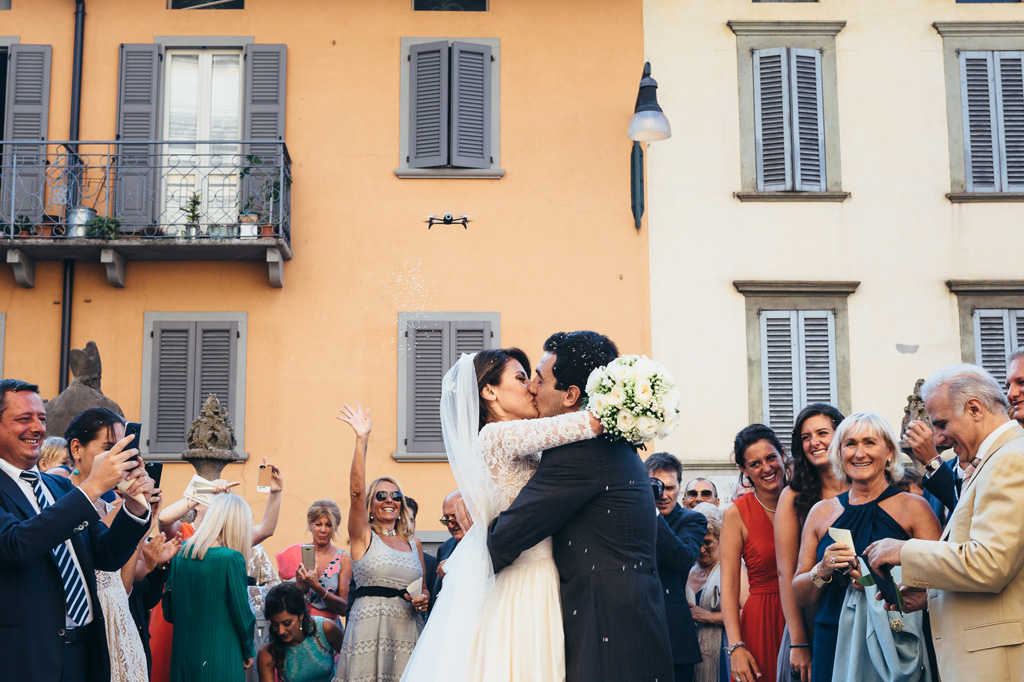 Fotografo Matrimonio Villa Caroli Zanchi Riccardo e Beatricesi baciano appassionatamente tra la folla festosa