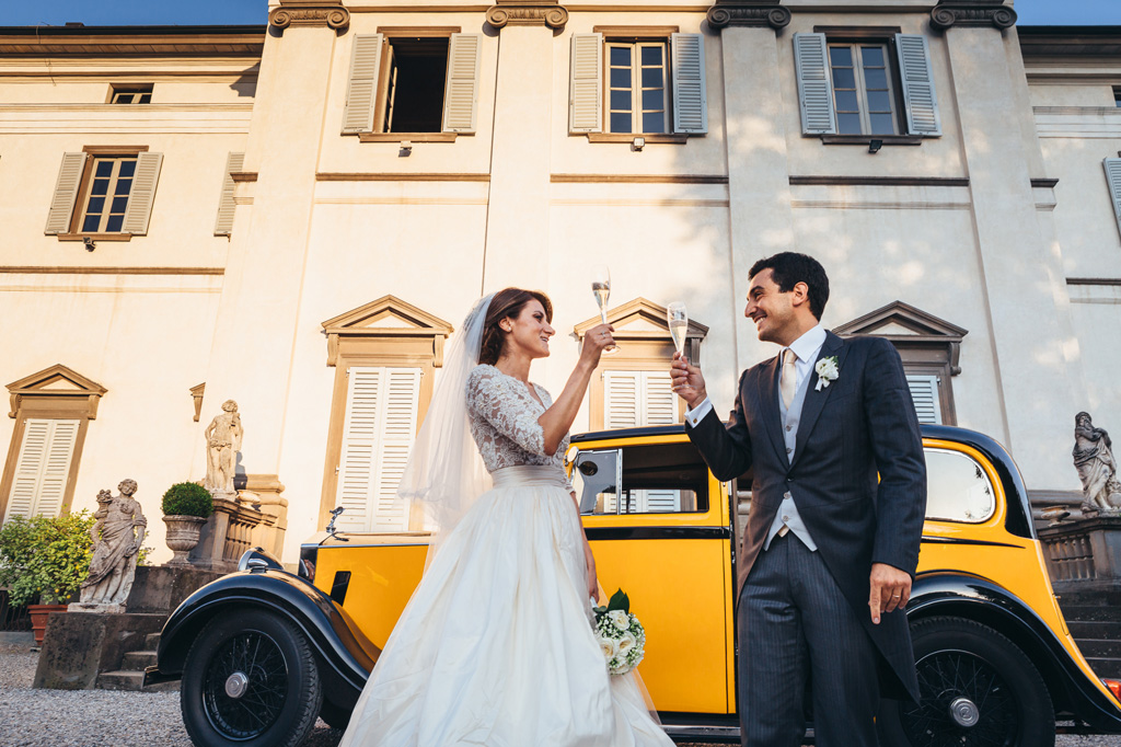 Fotografo Matrimonio Villa Caroli Zanchi Gli sposi appena usciti dalla macchina brindano a una lunga vita insieme