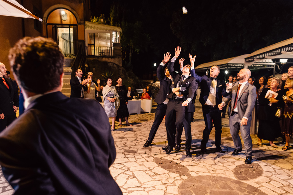Gli invitati acchiappano il bouquet dello sposo