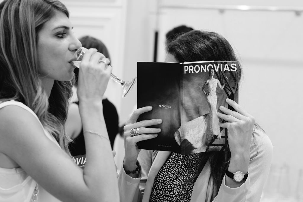 Pronovias Due invitate leggono il catalogo di Pronovias in negozio