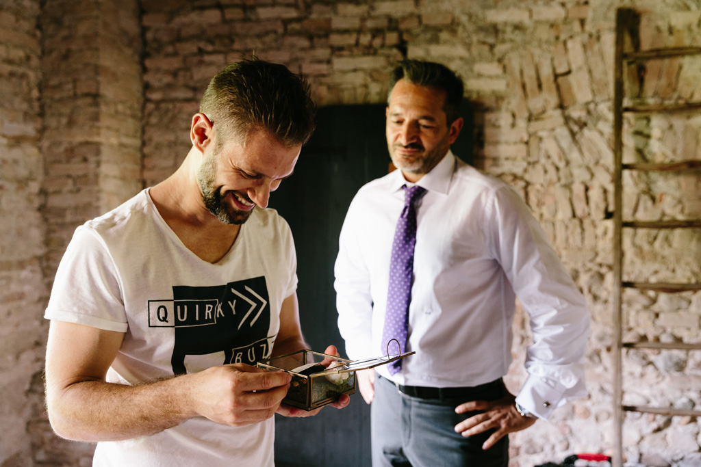 Fotografo Matrimonio Convento Dell'Annunciata Medole Lo sposo apre il regalo della sposa e legge il biglietto sorridendo