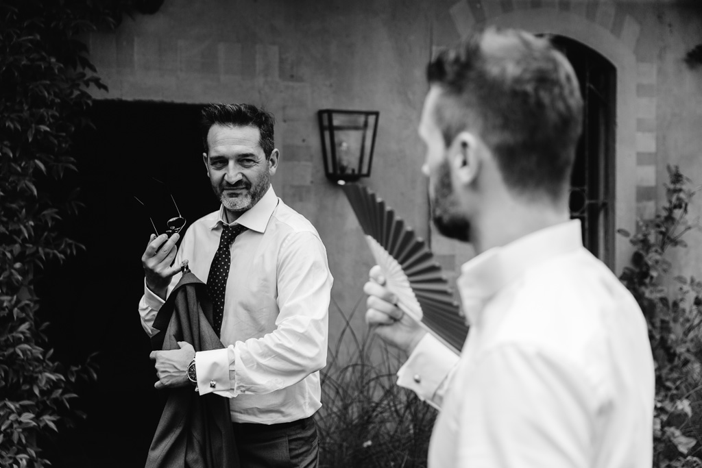 Fotografo Matrimonio Convento Dell'Annunciata Medole Lo sposo si fa aria con un ventaglio mentre parla con un amico