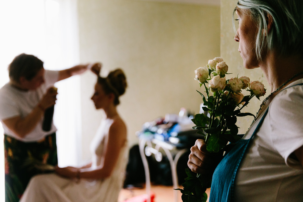 Fotografo Matrimonio Convento Dell'Annunciata Medole Ultimi ritocchi all'acconciatura della sposa mentre la truccatrice osserva con le rose in mano