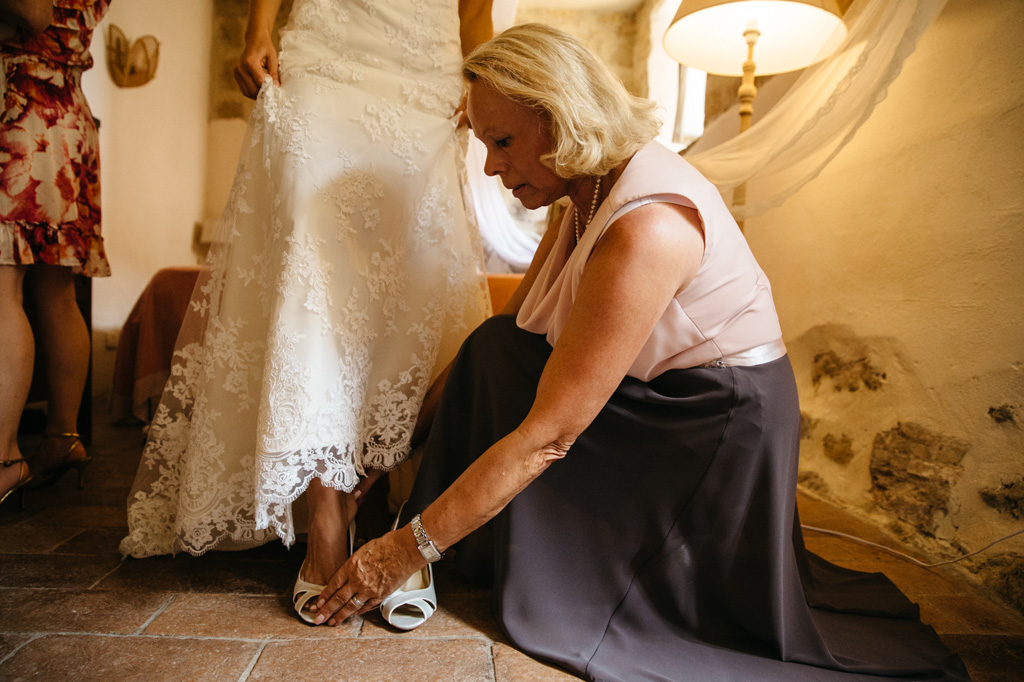 Fotografo Matrimonio Basilica San Galgano Toscana La mamma aiuta la sposa a infilare le scarpe