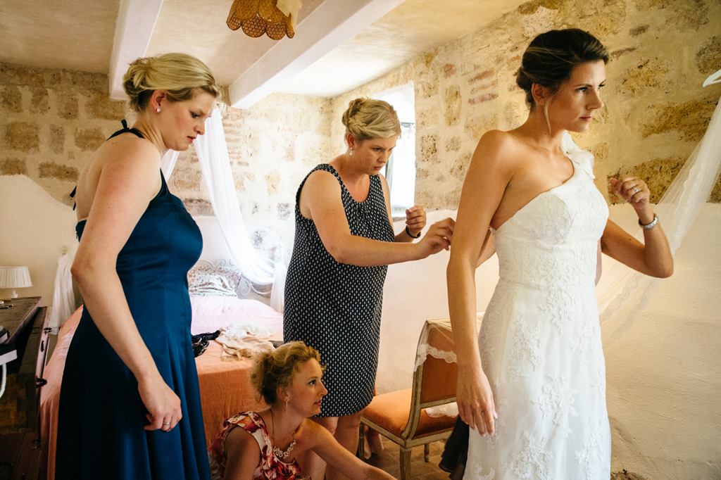 Fotografo Matrimonio Basilica San Galgano Toscana Le damigelle allacciano il vestito alla sposa