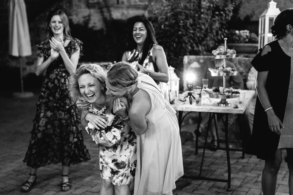 Fotografo Matrimonio Basilica San Galgano Toscana Le invitate si abbracciano divertite dopo il lancio del bouquet