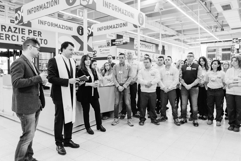 Fotografo Evento Milano Ottimax San Giuliano Milanese Un prete benedice il negozio con la lettura di alcune preghiere in uno scatto del fotografo di inaugurazioni ed eventi Della Savia