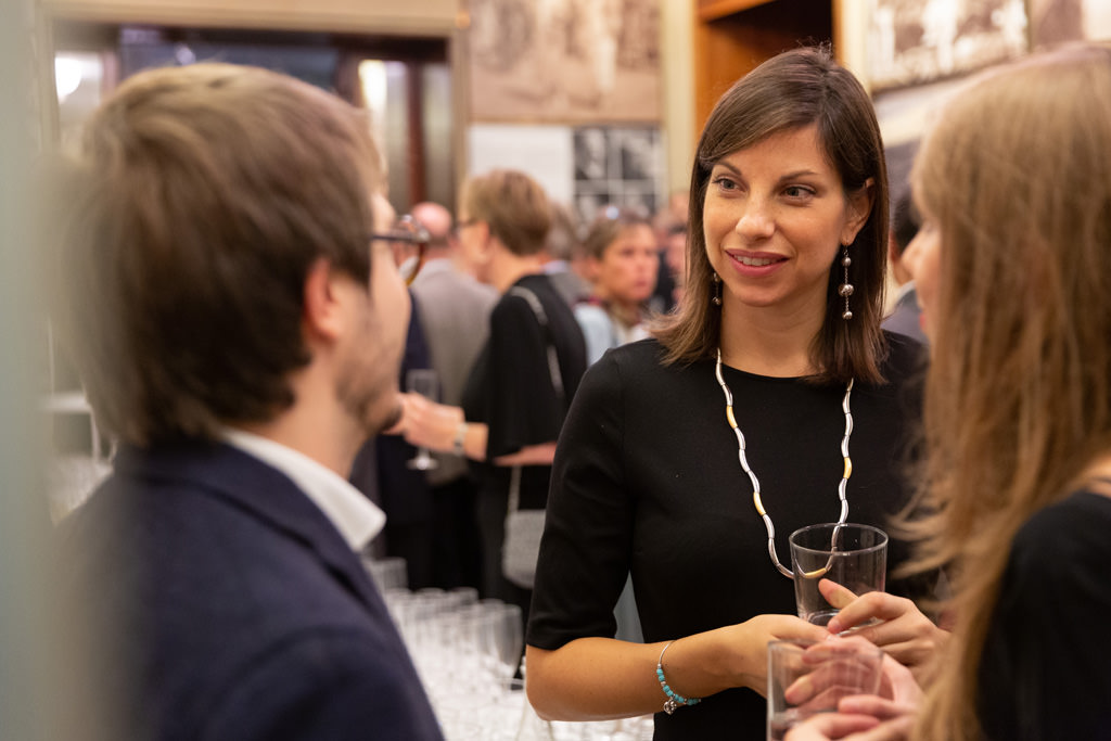 Fotografo Cena Aziendale Milano EUGA Villa Necchi Campiglio Un'invitata conversa in compagnia