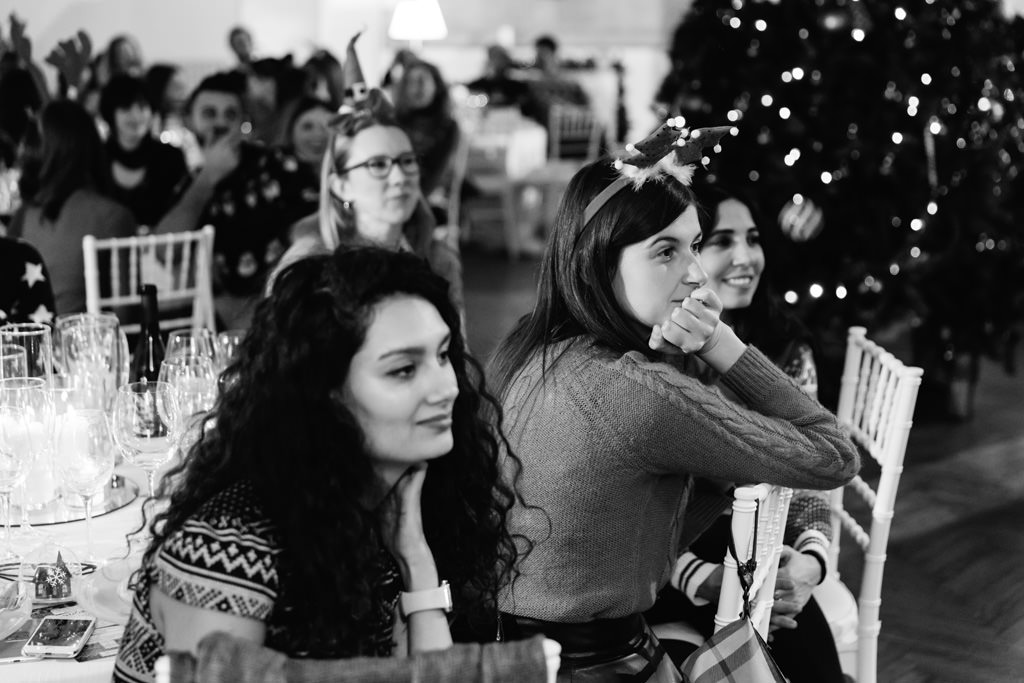 Fotografo Evento Milano Cena Aziendale Filologico Pandora Le invitate seguono con attenzione l'estrazione dei regali natalizi