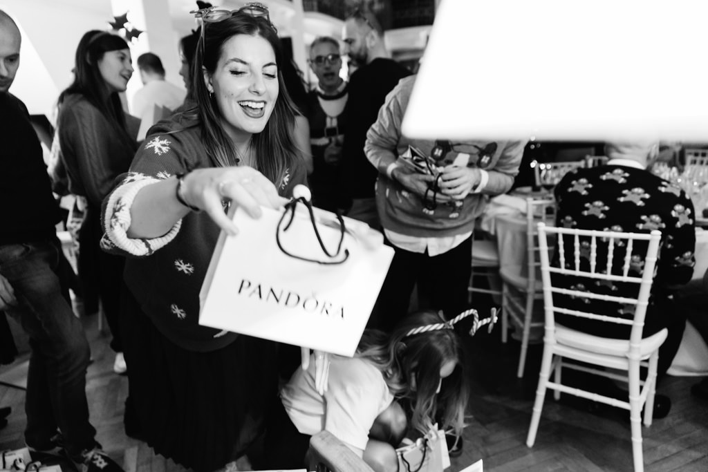 Fotografo Evento Milano Cena Aziendale Filologico Pandora Un'invitata scarta il regalo di pandora ritratta dal fotografo Dlela Savia,