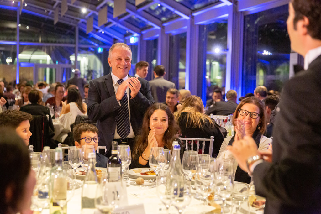 Fotografo Cena Aziendale Milano EUGA Villa Necchi Campiglio Gli invitati applaudono divertiti l'ospite