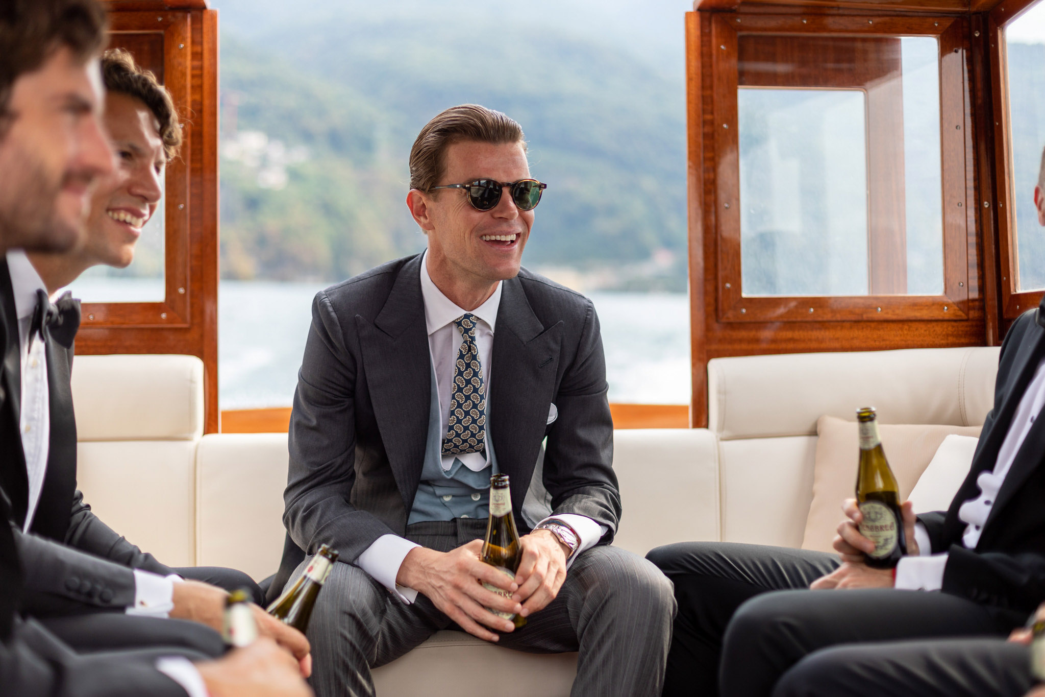 Destination Wedding Photographer Lake Como Uno sposo su una barca sul lago di como insieme agli invitati