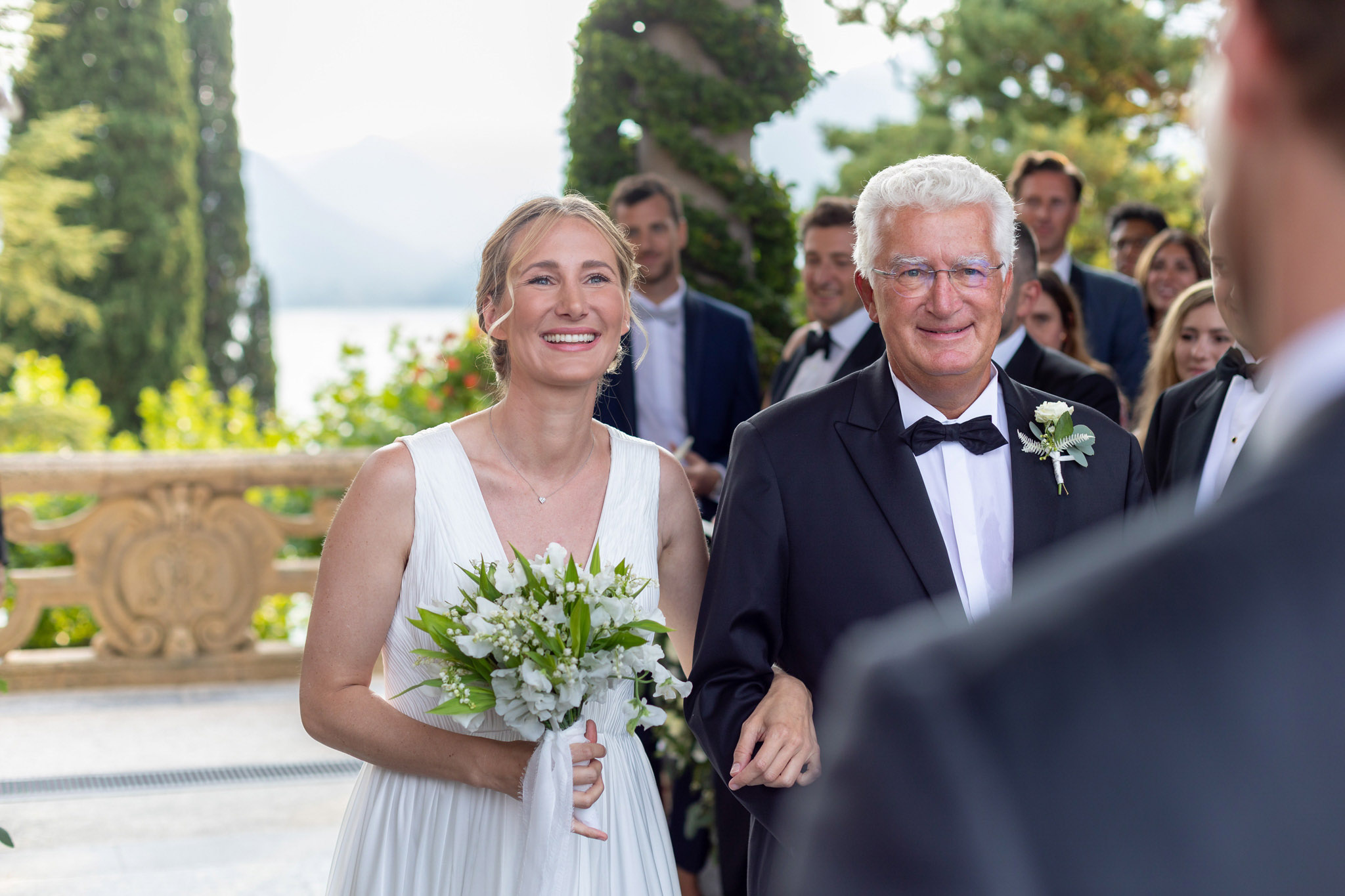 Destination Wedding Photographer Lake Como Una sposa insieme al padre ai piedi dell'altare