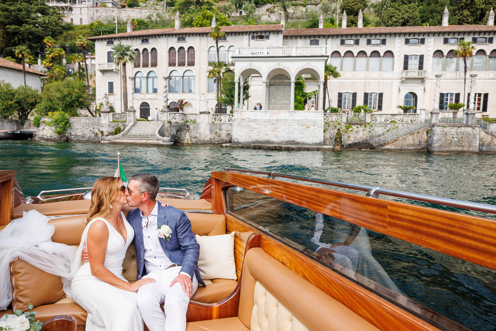 Destination Wedding Photographer Como Lake Gli sposi che si baciano in barca sul lago di como al loro matrimonio