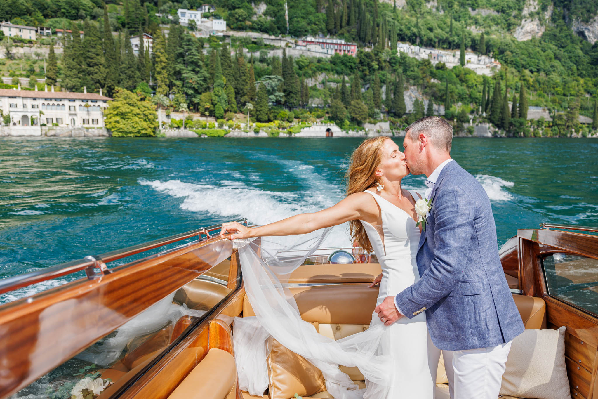 Destination Wedding Photographer Como Lake Gli sposi che si baciano in barca sul lago di como al loro matrimonio
