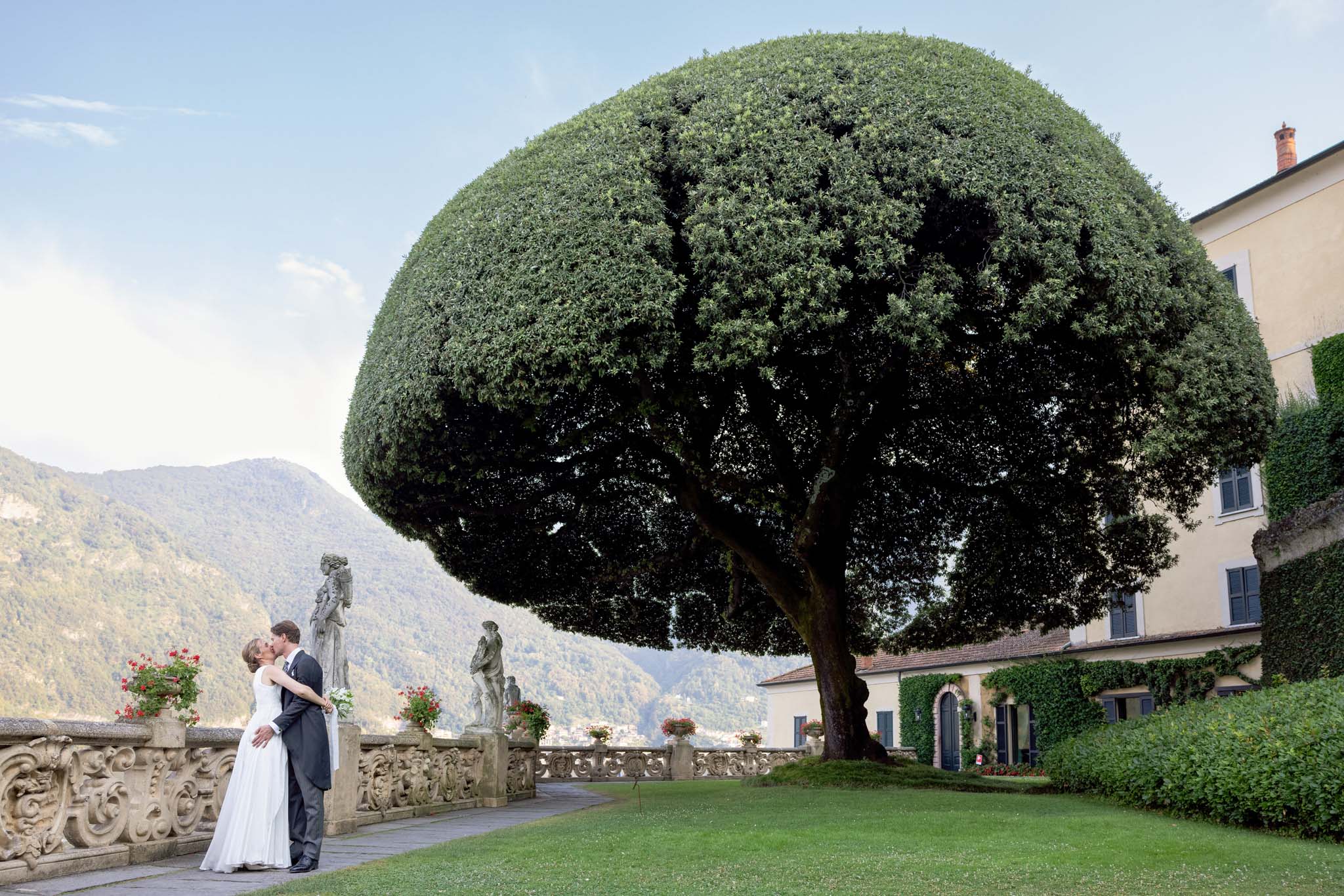 Destination Wedding Photographer Lake Como Gli sposi che si baciano nel giardino di una villa sul lago di Como