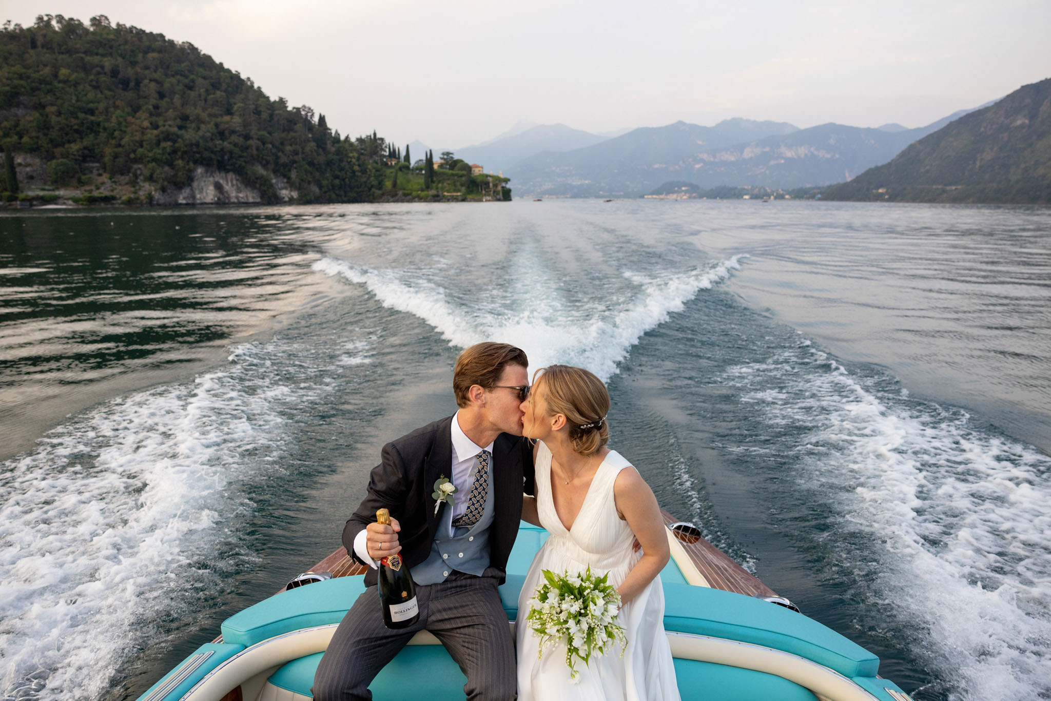 Destination Wedding Photographer Lake Como Due sposi che si baciano su una barca sul lago di Como