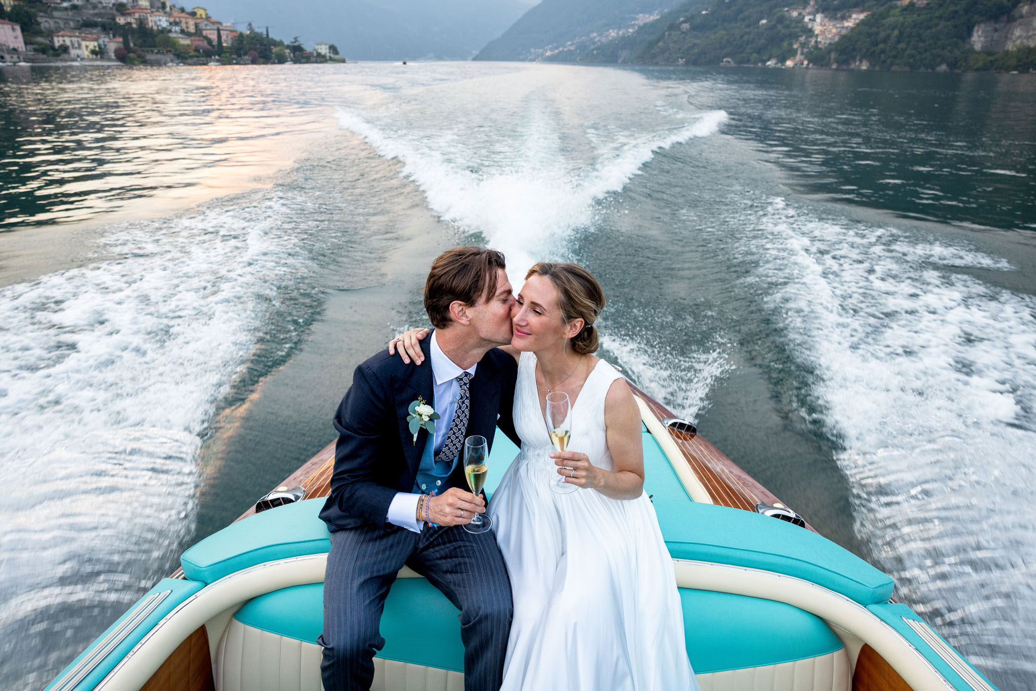Destination Wedding Photographer Lake Como Due sposi che si baciano su una barca sul lago di Como